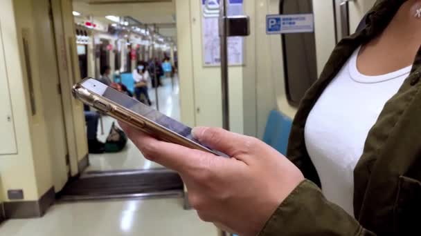 アジアの女性は 彼女が彼女の停車駅に到着するのを待つと アクティブな地下鉄でスマートフォンを使用して ソーシャルネットワークをチェックし 電話デバイス上で行われたテキストを書き込みます — ストック動画