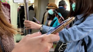 Taipei, Tayvan-15 Mart 2020: 4 K, Asyalı kadın koronavirüsü korumak ve aktif metroda akıllı telefon kullanmak için cerrahi maske takıyor. COVID19 'un iyileşmesine yardım etmek için sağlık hizmeti. Bulaşıcı bulaşıcı konsept - Dan
