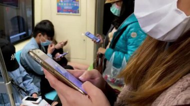 Taipei, Tayvan-15 Mart 2020: 4 K, Koronavirüs 'ü korumak için maske takan Asyalı bir kadın ve metro istasyonuna varmayı beklerken akıllı telefon kullanıyor. Telefon aygıtı-Dan 'de yapılan metni yaz