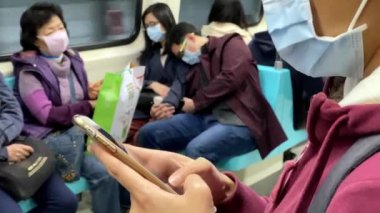 Taipei, Tayvan-22 Şubat 2020: 4K, Asyalı kadın akıllı telefon kullanıyor ve 2019-NCoV enfeksiyonuna karşı maske takıyor. Wuhan, Çin 'de bulunan Coronavirus romanından. - Dan.
