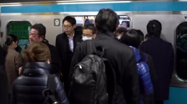 Tokyo, Japonya-04 Şubat 2017: 4K, metroda yoğun saatlerde cerrahi maske takan Asyalılar. Tren istasyonunda bir sürü insan var. Japon gezginler metroya biniyor. COVID19 salgını - Dan