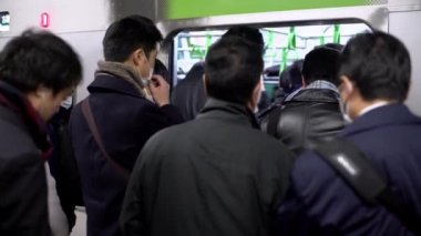 Tokyo, Japonya-04 Şubat 2017: 4K, Asyalı kalabalık metro trafiğinde seyahat ediyor. Tren istasyonunda bir sürü yolcu vardı. Japon gezginler iş için metroya biner.