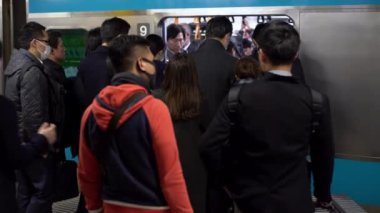 Tokyo, Japonya-04 Şubat 2017: 4K, kalabalık kalabalık metroda sabah trafiği sırasında. Metroya binen bir sürü yolcu. Tren istasyonunda yürüyen banliyö sakinleri.