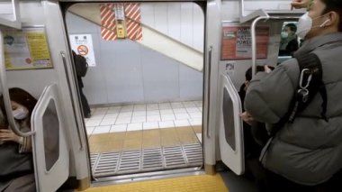 Tokyo, Japonya-04 Şubat 2017: 4K, Asyalı kalabalık metro trafiğinde seyahat ediyor. Tren istasyonunda bir sürü yolcu vardı. Japon gezginler iş için metroya biner.