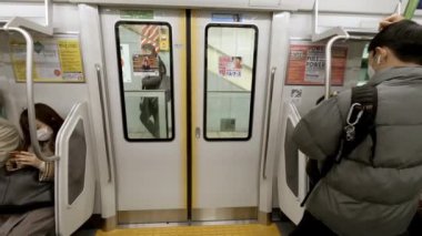 Tokyo, Japonya-04 Şubat 2017: 4K, Japon metro vagonunun peronda açıldığı iç mekan. İnsanlar metronun içinde duruyor. Yolcular toplu taşıma araçlarıyla seyahat ederler. - Dan.