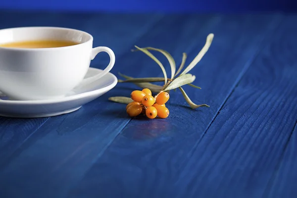 Reife Sanddornbeeren neben einer Tasse mit Tee — Stockfoto