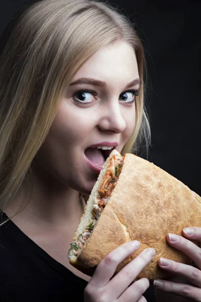 Retrato de una hermosa joven mordiendo un sándwich — Foto de Stock