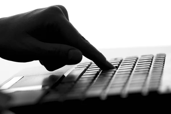 Silhouette of the finger of a female hand press a key on the keyboard of the netbook — Stock Photo, Image