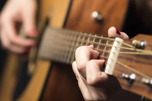 Junge Frau mit Fingern an Gitarrensaiten geklemmt — Stockfoto