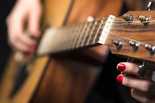 Junge Frau mit Fingern an Gitarrensaiten geklemmt — Stockfoto