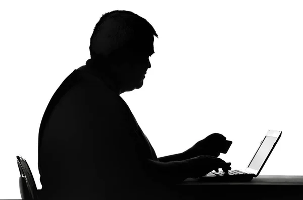 Silhouette di un uomo che digita su un calcolo una password per la scheda — Foto Stock