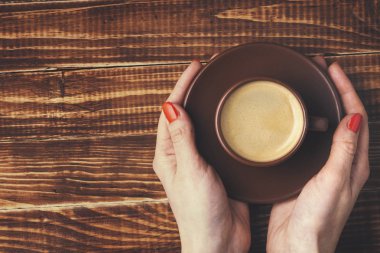bir fincan kahve ile bir daire tutan kadınların elleri