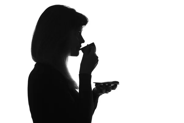 Силуэт молодой женщины, пьющей кофе — стоковое фото
