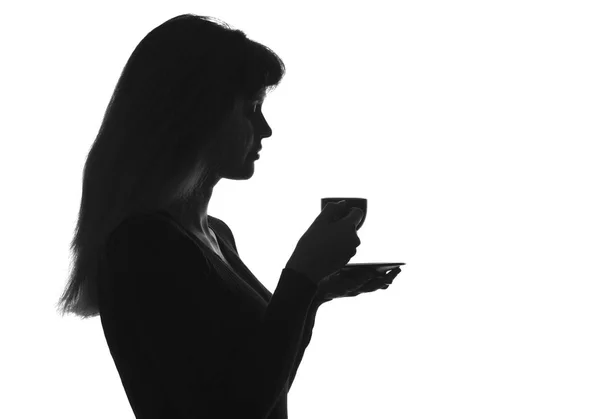 Silueta retrato de una hembra con una taza de bebida en un platillo — Foto de Stock