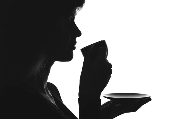 Silhouette ritratto di una femmina con una tazza di bevanda su un piattino — Foto Stock