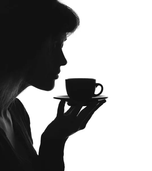 Silhouette portrait of a female with a cup of hot drink on a saucer — Stock Photo, Image