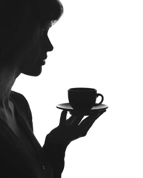 Silhouette portrait of a female with a cup of hot drink on a saucer — Stock Photo, Image