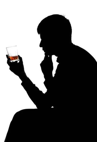 Silueta de un hombre mirando una bebida alcohólica — Foto de Stock
