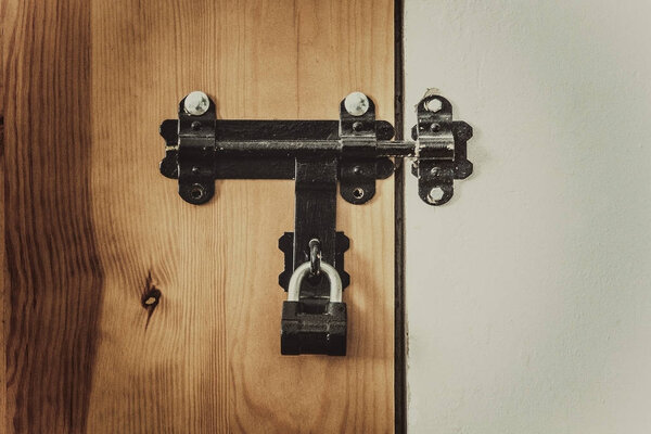 Old latch on a door with a padlock