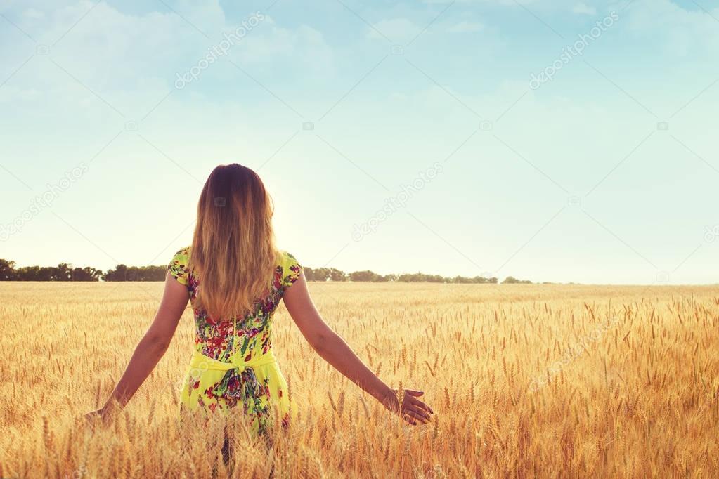 woman walking through the field and stroking ears