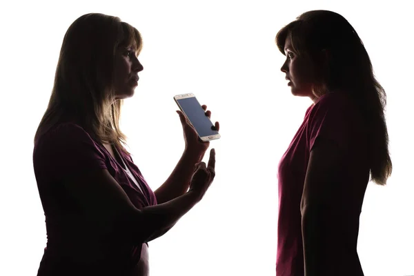 Силуэт возмущенной матери с телефоном дочери, подросток боится — стоковое фото