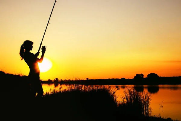 Silueta de una mujer pescadora al amanecer —  Fotos de Stock