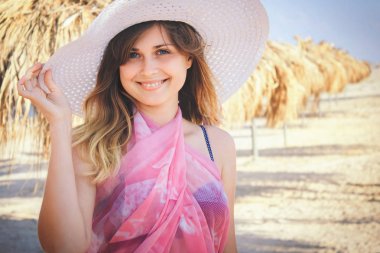 Denizde bir plajda şemsiye karşı şapkalı bir kadın portresi