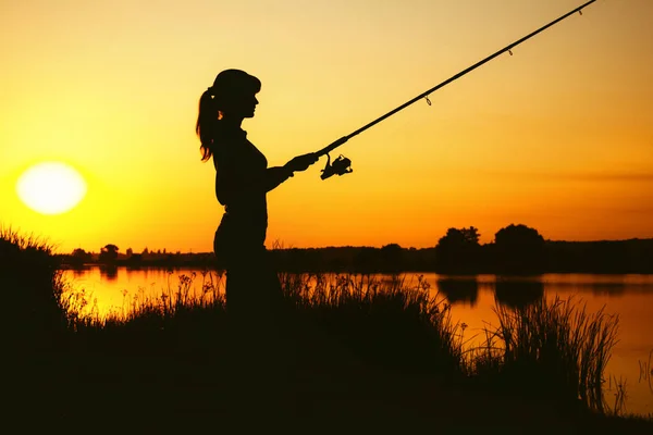 Silhouette di una donna impegnata nella pesca sportiva — Foto Stock