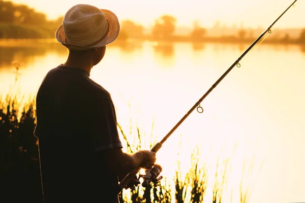 Silhouette di un uomo con un cappello impegnato nella pesca sportiva — Foto Stock