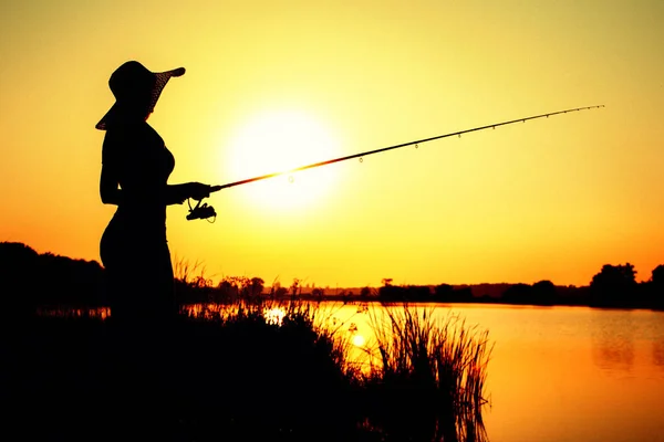 Silhouette of a woman in a hat engaged in sport fishing — Stock Photo, Image