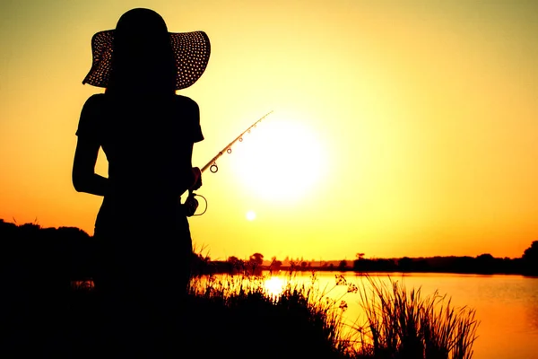 Silhouette einer Frau mit Angelrute in der Morgendämmerung — Stockfoto