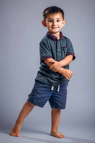 Studioporträt eines kleinen Jungen, der vor grauem Hintergrund posiert — Stockfoto