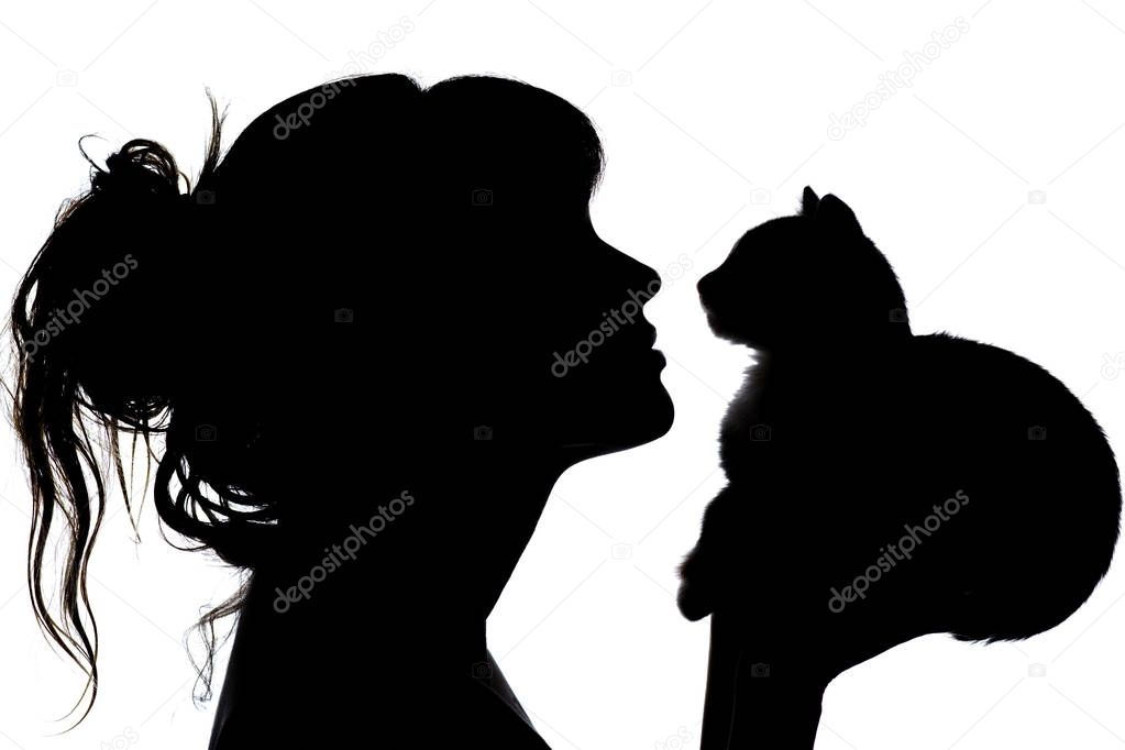 silhouette of a beautiful woman with wavy hair that nose to nose with a small kitten in her arms, the concept of caring for animals, favorite pets