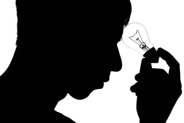 Schwarz-weiße Silhouette eines jungen Mannes in Depressionen, der darüber nachdenkt, ein Problem mit einer Lampe in Stirnnähe auf weißem isolierten Hintergrund zu lösen, Konzeptideen, Gedankenlampe — Stockfoto