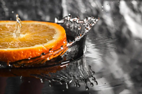 an orange ring with splashes of water, a fruit with splashes