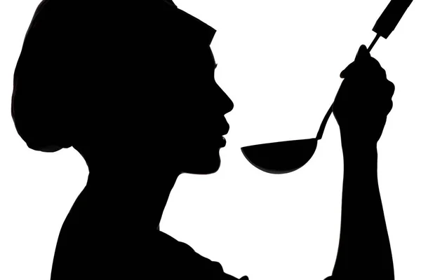 Silhouette di donna che cucina in un berretto, profilo di una ragazza che soffia a minestra su mestolo su uno sfondo bianco isolato — Foto Stock