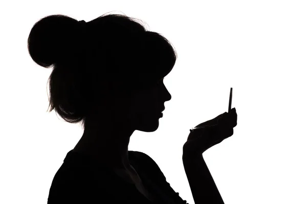 Silhouettenprofil eines Frauengesichts, das in einen Taschenspiegel blickt, das Konzept der Schönheit und Mode — Stockfoto