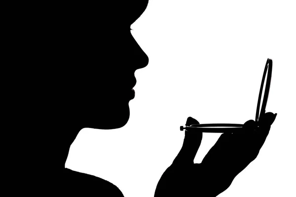 Silhouette profile of a woman face looking in a pocket mirror, the concept of the beauty and fashion — Stock Photo, Image