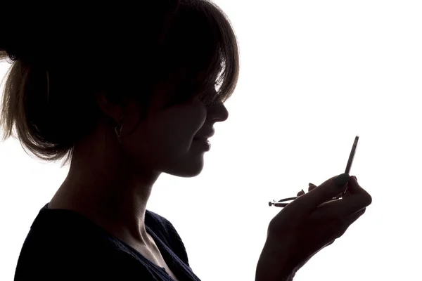 Perfil de silueta de una cara de mujer mirando en un espejo de bolsillo, el concepto de la belleza y la moda — Foto de Stock