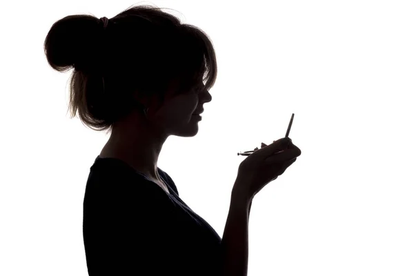 Silhouette of a thoughtful sad woman with hand near her forehead