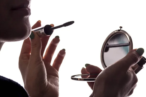 Silhouette de femme faisant maquillage, fille avec mascara et miroir de poche dans les mains — Photo