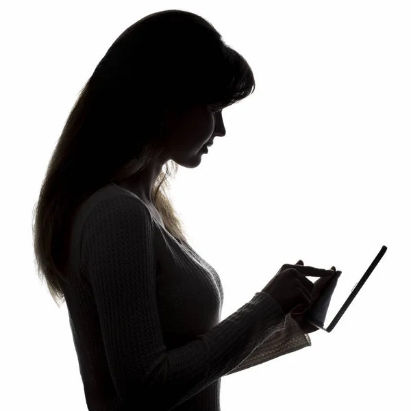 Силуэт женского профиля с планшетом, девушка с электронным устройством в руках — стоковое фото