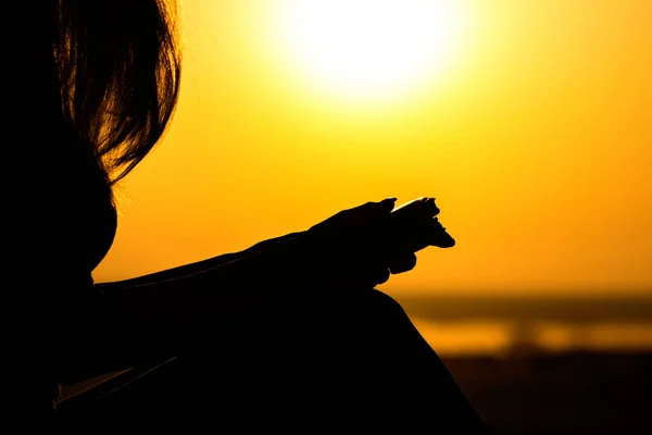 Silhueta das mãos da mulher orando a Deus na natureza witth a Bíblia ao pôr do sol, o conceito de religião e espiritualidade — Fotografia de Stock