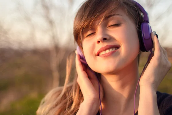 Ansikte av kvinna i hörlurar, flicka vänligt musiken på naturen — Stockfoto