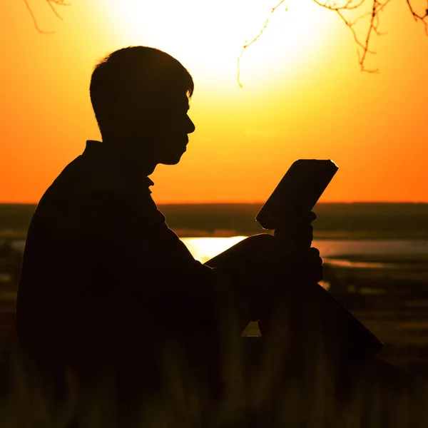 Silhouette di un giovane con una Bibbia, maschio meditando e cercando risposte nelle Scritture, il concetto di religione e spiritualità — Foto Stock