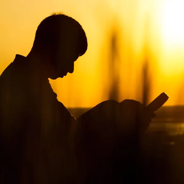Silhouette di un giovane con una Bibbia, maschio che prega Dio in natura, il concetto di religione e spiritualità — Foto Stock