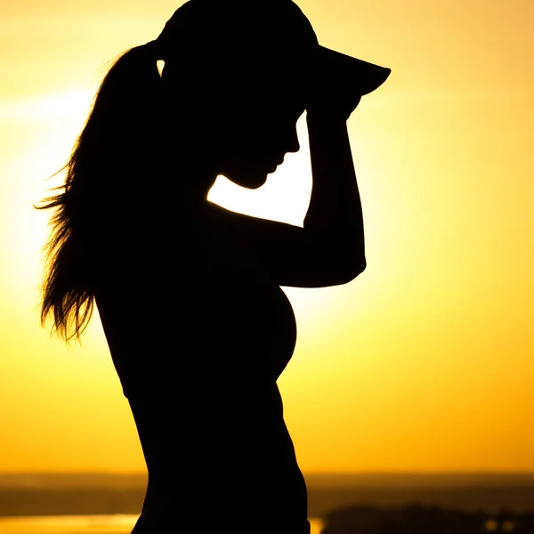 Silhouette di una donna stanca dopo la corsa al tramonto, una ragazza asciuga il sudore dal viso, concetto di sport e assistenza sanitaria — Foto Stock