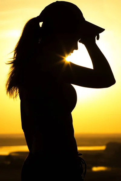 Silhueta de uma mulher cansada depois de correr ao pôr do sol, uma menina limpa o suor do rosto, esporte conceito e cuidados de saúde — Fotografia de Stock