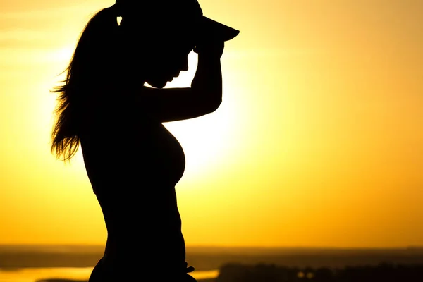 Silhouette einer Frau, die nach Sonnenuntergang müde ist, ein Mädchen wischt sich den Schweiß aus dem Gesicht, Konzeptsport und Gesundheitsfürsorge — Stockfoto