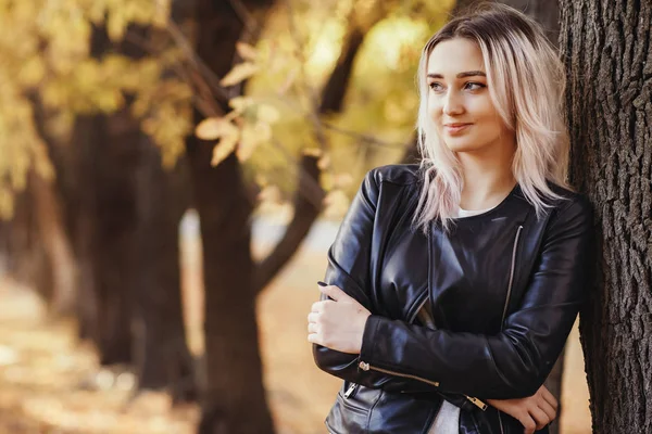 Portrait of a beautiful girl leaning on a tree trunk, a young woman walks in the autumn park on nature — Stock Photo, Image